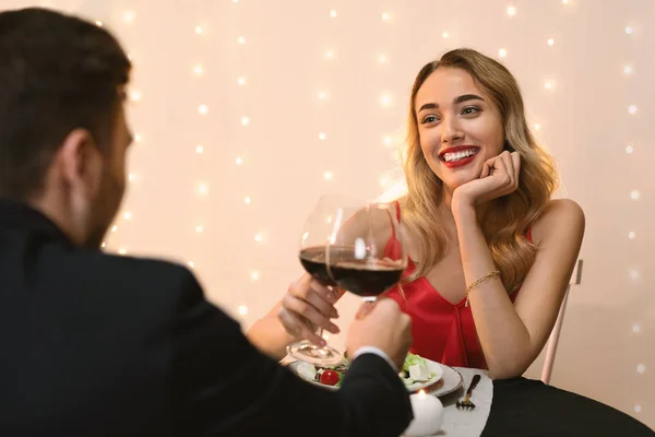 Romantik çift restoranda yemek yiyor, şarap içiyor ve akşam yemeğinin tadını çıkarıyor. — Stok fotoğraf