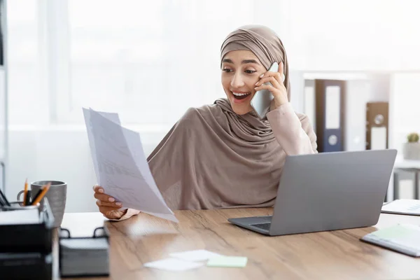 Millennial moslim zakenvrouw in gesprek op mobiele telefoon en het controleren van documentatie in het kantoor — Stockfoto