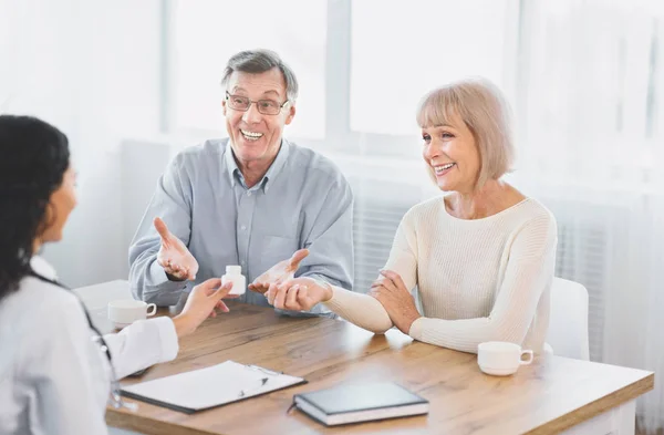 Verpleegster geeft senior vrouw plastic pil pot op haar kantoor — Stockfoto