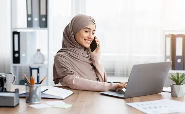 Jonge Arabische zakenvrouw praten op mobiele telefoon en het gebruik van laptop in Office — Stockfoto