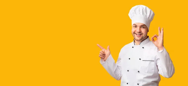 Chef gesticolando Ok puntando il dito sullo spazio di copia, sfondo giallo — Foto Stock