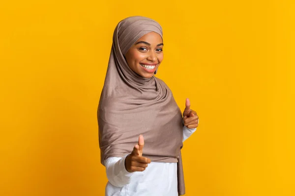 Sonriente mujer afro musulmana en pañuelo para la cabeza señalando los dedos en la cámara — Foto de Stock
