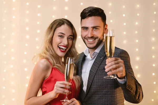 Jeune couple heureux lever des verres de champagne et regarder la caméra — Photo