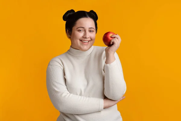 Gelukkig mooi plus grootte meisje poseren met appel in de hand — Stockfoto
