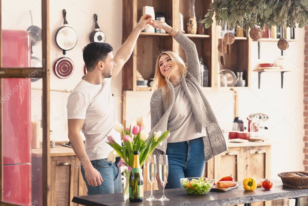 Young pair dancing at home on kitchen