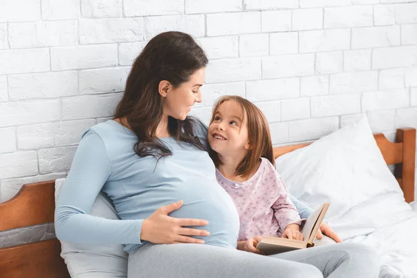 Anaokulundaki kız hamile annesiyle kitabı tartışıyor. — Stok fotoğraf
