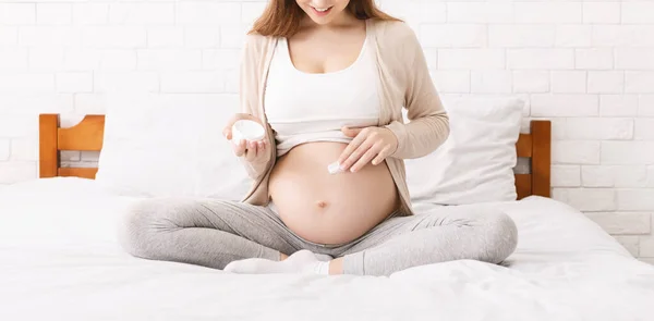 Zwangere vrouw hydrateert haar buik met lotion, panorama — Stockfoto