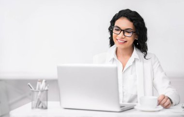 Smiling girl drinking tea and using personal computer