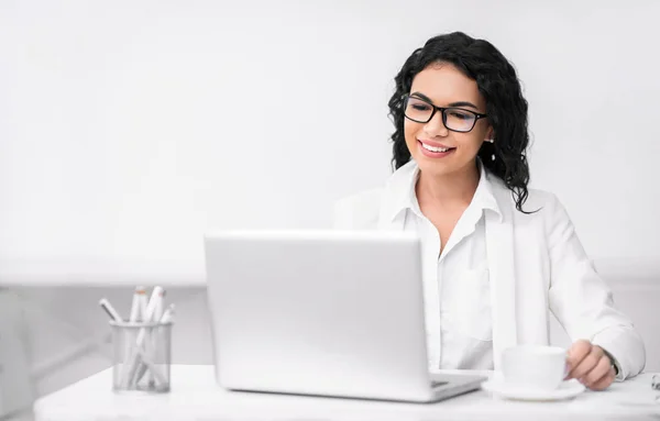 Smiling girl drinking tea and using personal computer — 스톡 사진