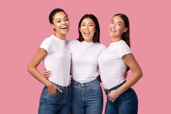 Tres niñas milenarias abrazando de pie sobre fondo rosa, Studio Shot — Foto de Stock