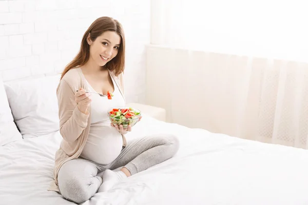 Wanita hamil makan salad sayuran alami di tempat tidur — Stok Foto