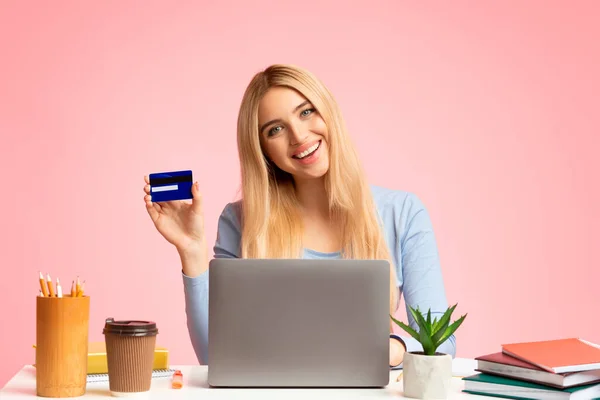 Молода жінка тримає кредитну картку і використовує ноутбук — стокове фото