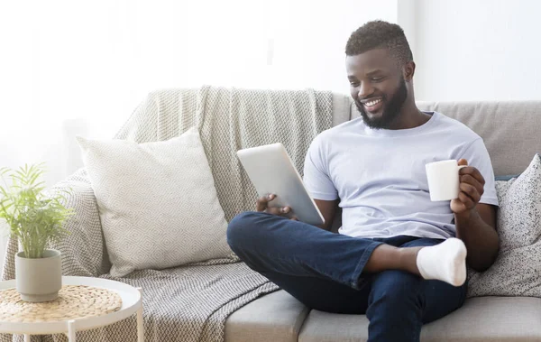 Χαρούμενα μαύρο άνδρα ανάγνωση ειδήσεων σε ψηφιακή tablet με καφέ — Φωτογραφία Αρχείου