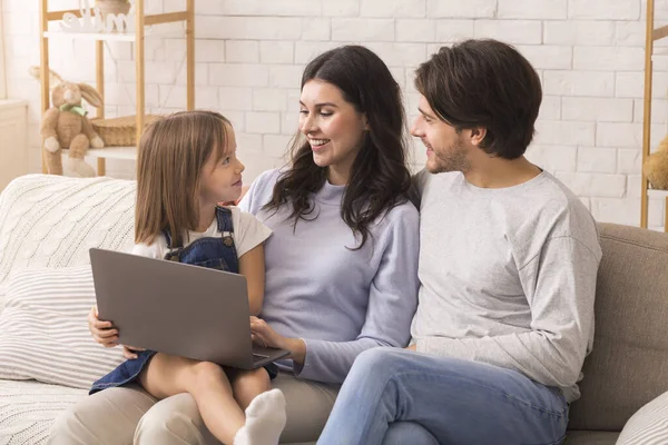 Portrait of young parents and their little daughter using laptop together — 스톡 사진