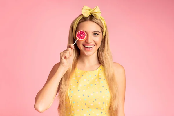 Spännande flicka som håller lollypop på rosa studio vägg — Stockfoto