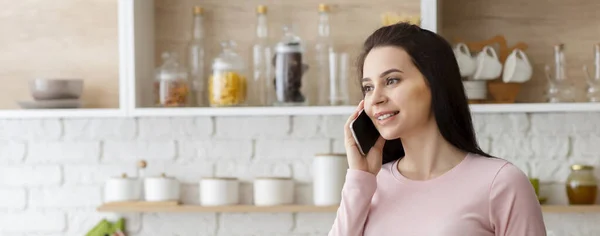 Jonge vrouw praten op mobiele telefoon in keuken interieur — Stockfoto