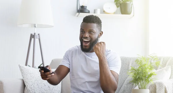 Känslomässig afrikansk fotboll fan titta på fotboll på TV hemma — Stockfoto