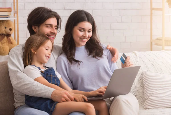 Família alegre encomendar coisas on-line com laptop e cartão de crédito — Fotografia de Stock