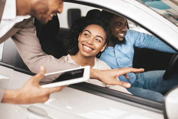 Щаслива пара купує автомобіль розмовляє з продавцем сидячи в авто — стокове фото