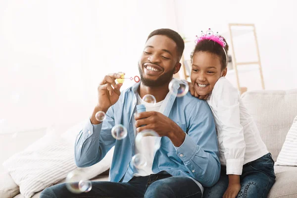 Afroamerikansk pappa och dotter blåser såpbubblor tillsammans — Stockfoto