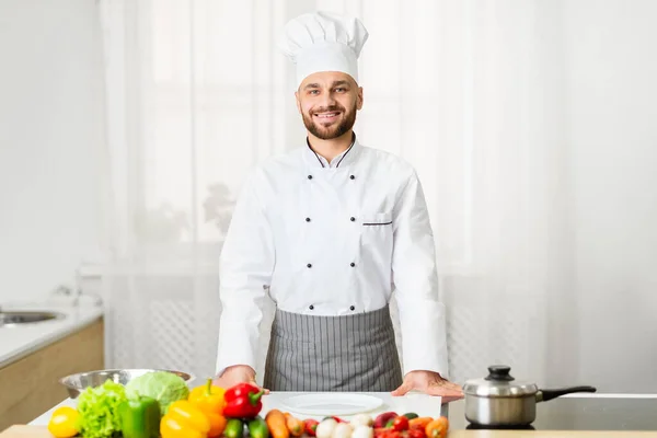 Maschio chef in uniforme sorridente in piedi in cucina — Foto Stock