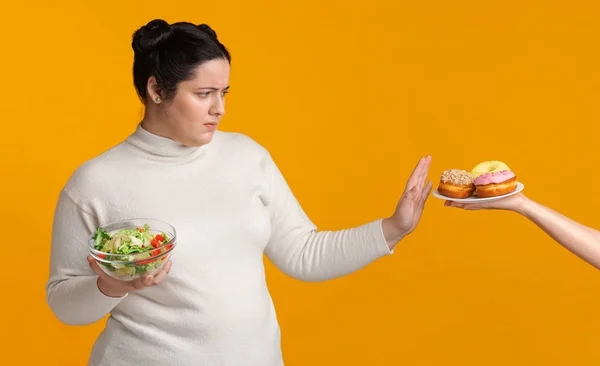 Baculatá dívka odmítá nezdravé jídlo, drží misku s čerstvým zeleninovým salátem — Stock fotografie