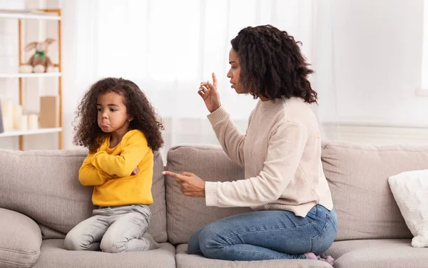 Mãe negra repreendendo filha sentada no sofá em casa — Fotografia de Stock