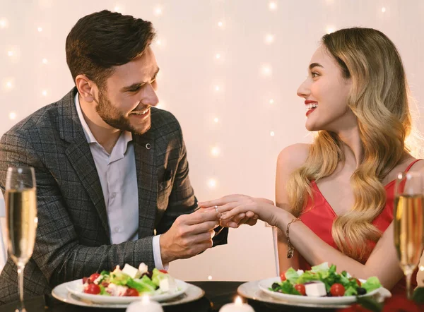 Ευτυχισμένος άντρας βάζει δαχτυλίδι αρραβώνων στις φιλενάδες του στο ρομαντικό δείπνο. — Φωτογραφία Αρχείου