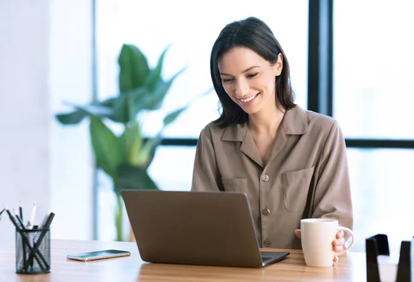 Ritratto di donna sorridente che lavora su laptop con tè — Foto Stock
