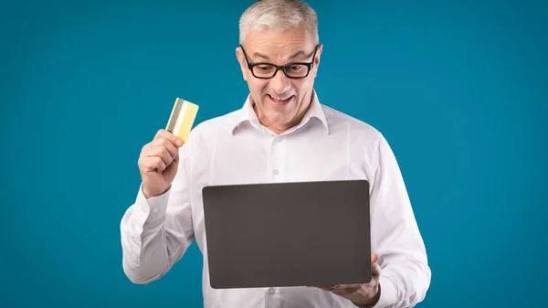 Šťastný dospělý muž držící kreditní kartu a počítač — Stock fotografie