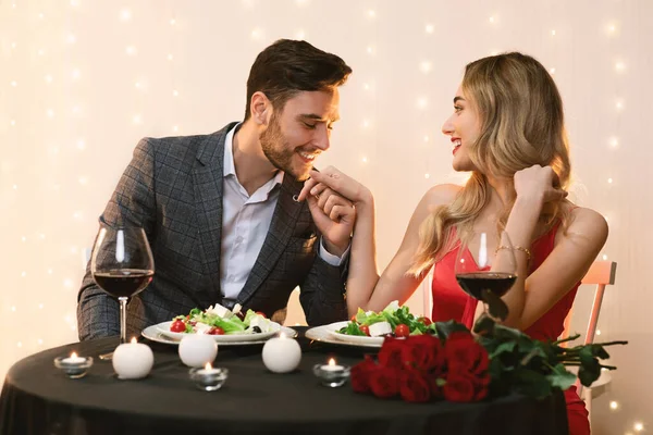 Romántico hermosa pareja comedor en restaurante, hombre cariñoso besar novias mano — Foto de Stock