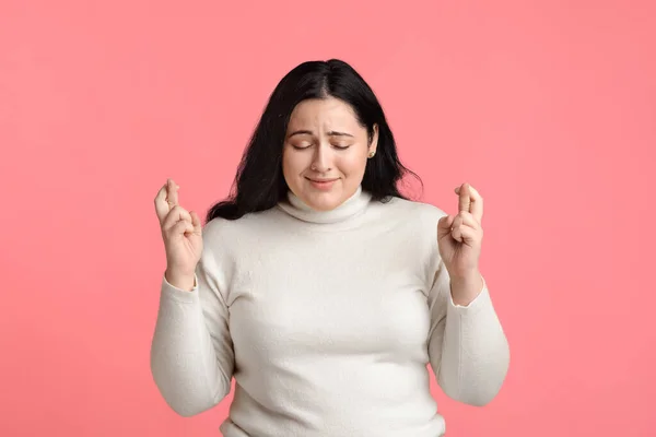 Retrato de una mujer joven con sobrepeso suplicando por algo con los dedos cruzados — Foto de Stock