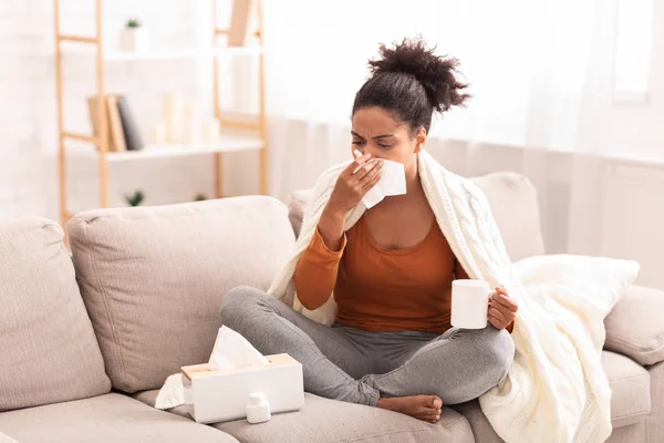 Sick Afro Woman Blowing Nose In Tissue Sitting On Sofa — Stock Photo, Image