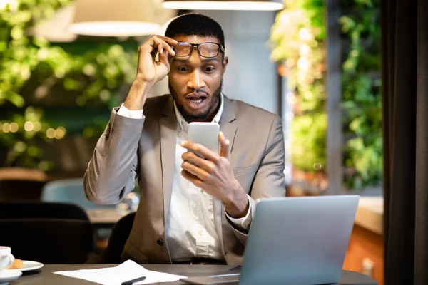 Afro chico de negocios leyendo sms impactantes celebración de teléfono —  Fotos de Stock