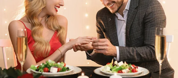 Nierozpoznawalny mężczyzna oświadczający się swojej dziewczynie w restauracji, zakładający pierścionek — Zdjęcie stockowe