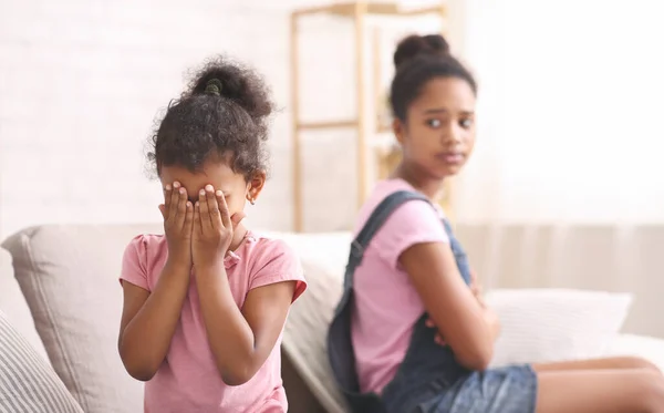 En liten afrikansk flicka som gråter hemma och blir förolämpad av sin syster. — Stockfoto