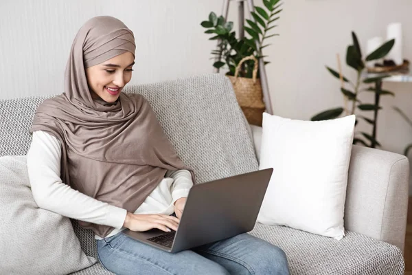 Evde dizüstü bilgisayar kullanan tesettürlü genç Müslüman kadın. — Stok fotoğraf