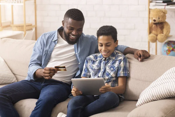 Χαρούμενο μαύρο πατέρα ψώνια σε απευθείας σύνδεση με τον γιο του χρησιμοποιώντας ψηφιακή ταμπλέτα — Φωτογραφία Αρχείου