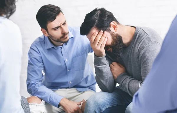 Miembros del grupo reconfortan al hombre adicto llorando en la sesión de rehabilitación — Foto de Stock