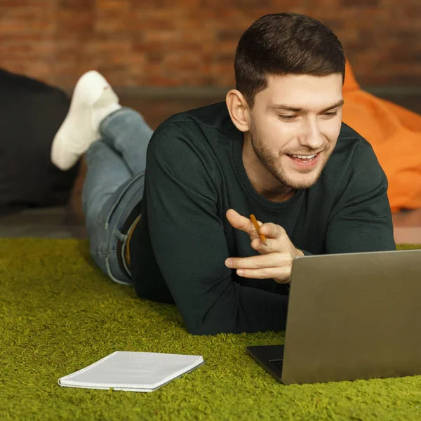 Man met behulp van laptop communiceren met klanten liggen op de vloer Indoor — Stockfoto