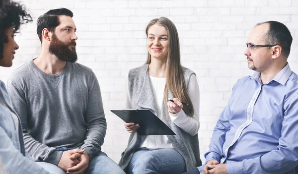 Psicoterapeuta hablando con los pacientes durante la sesión de terapia de grupo y tomando notas — Foto de Stock