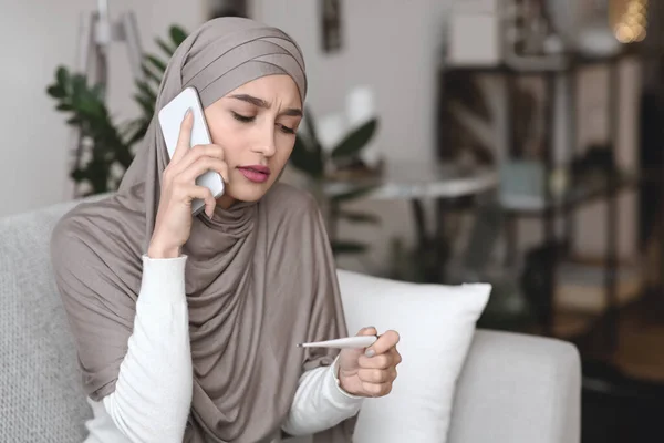 Ragazza araba malata che tiene il termometro, chiamando il medico di famiglia per ottenere una consultazione — Foto Stock