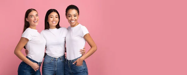 Tre ragazze miste che si abbracciano in posa su sfondo rosa Studio, Panorama — Foto Stock