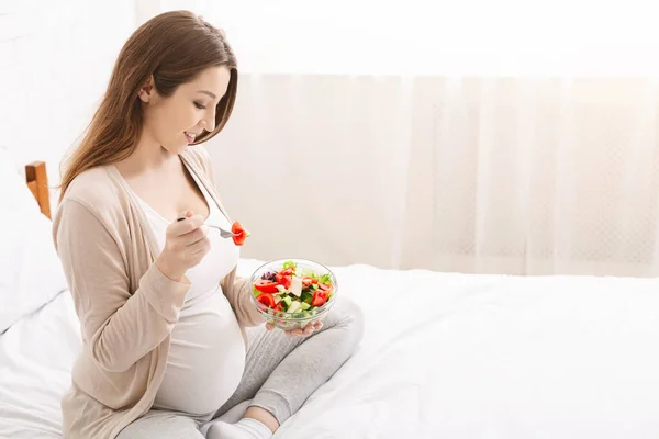 Wanita hamil menikmati sayuran segar salad di tempat tidur — Stok Foto