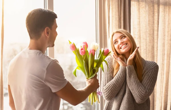 Homem dando buquê de tulipas rosa para sua bela esposa — Fotografia de Stock