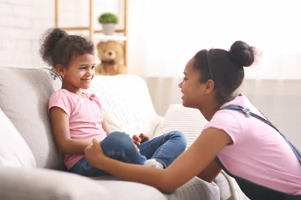 Africana adolescente chica hablando con su pequeña hermana en casa — Foto de Stock