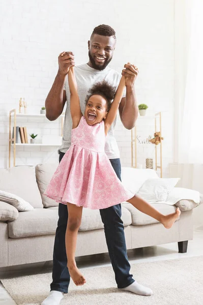 Emotionaler afrikanischer Vater hebt seine süße kleine Tochter hoch — Stockfoto