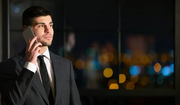 Empresario hablando por teléfono móvil de pie en la oficina nocturna — Foto de Stock