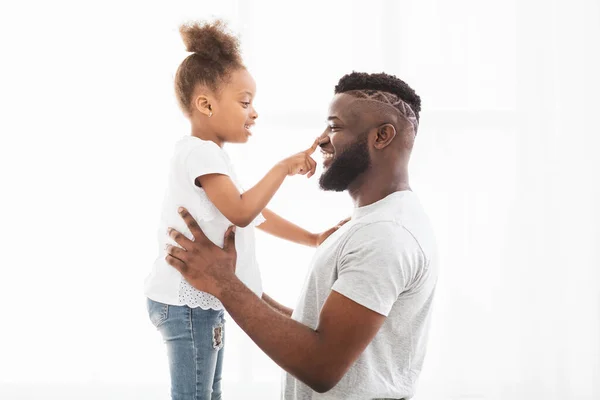 Nyfiken afro flicka röra hennes pappa näsa — Stockfoto