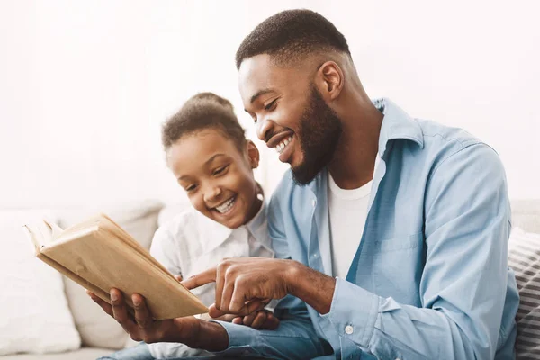 Cuidar a papá afroamericano leyendo libro a su linda hija — Foto de Stock